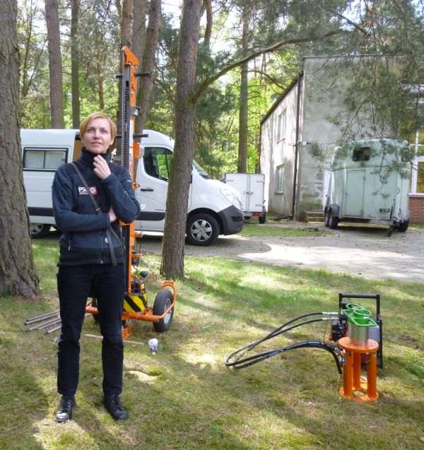 kobieta stojąca w lesie obok maszyny do wiercenia otworów