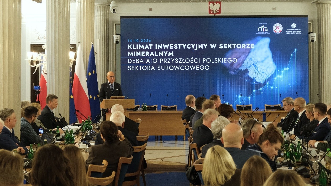 mężczyzna z mikrofonem w ręce podczas prelekcji, na tle ekranu